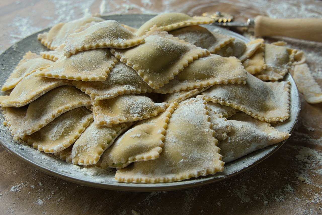 Ravioli freschi fatti in casa con ripieno cremoso di ricotta e spinaci su un tavolo di legno.
